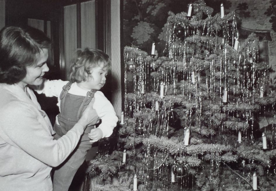 Weihnachten 1960er Jahre: Eine Mutter zeigt ihrer Zweijährigen den mit Lametta geschmückten Baum