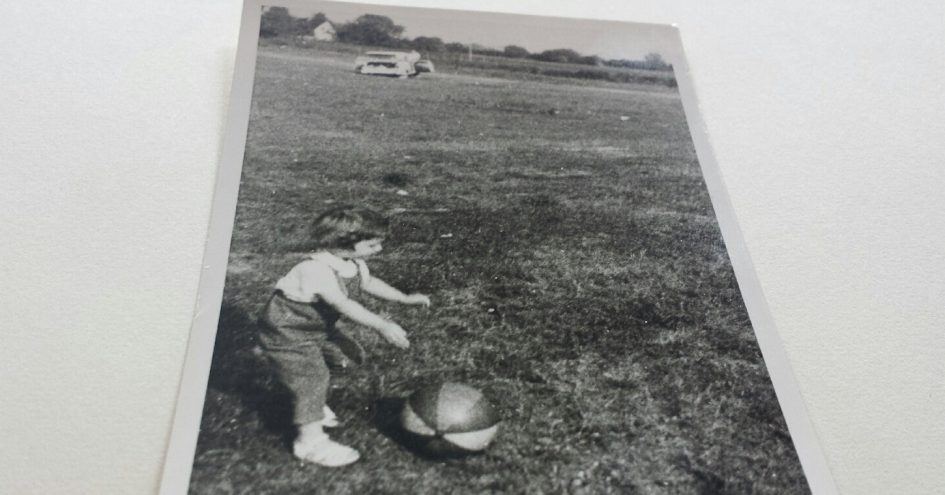 Lebenserinnerung an die 60iger Jahre: Mädchen spielt mit einem Ball auf einer großen Wiese, s/w-Foto